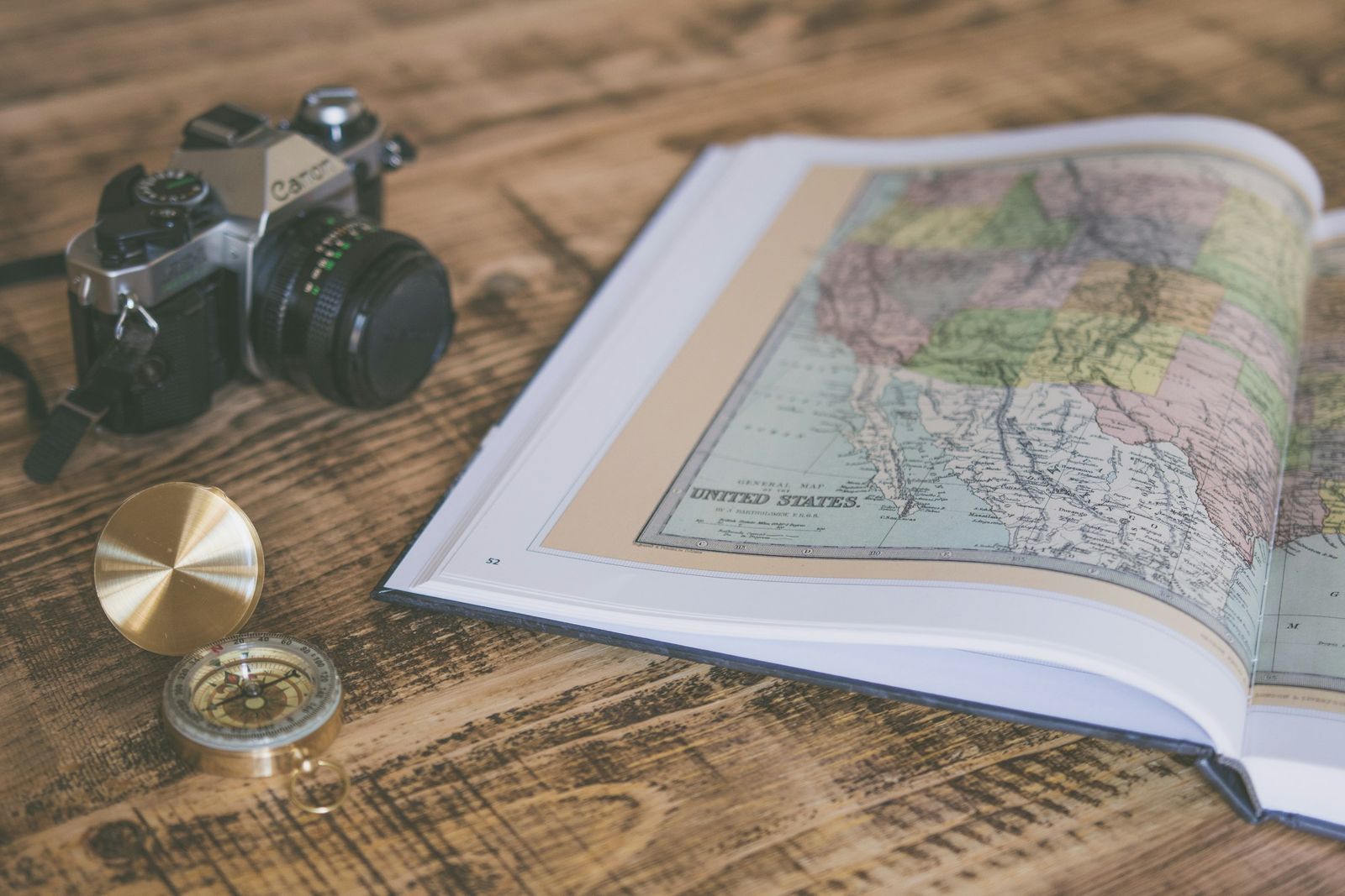 Cámara, brújula y mapa antiguo sobre una mesa de madera, preparados para organizar un viaje