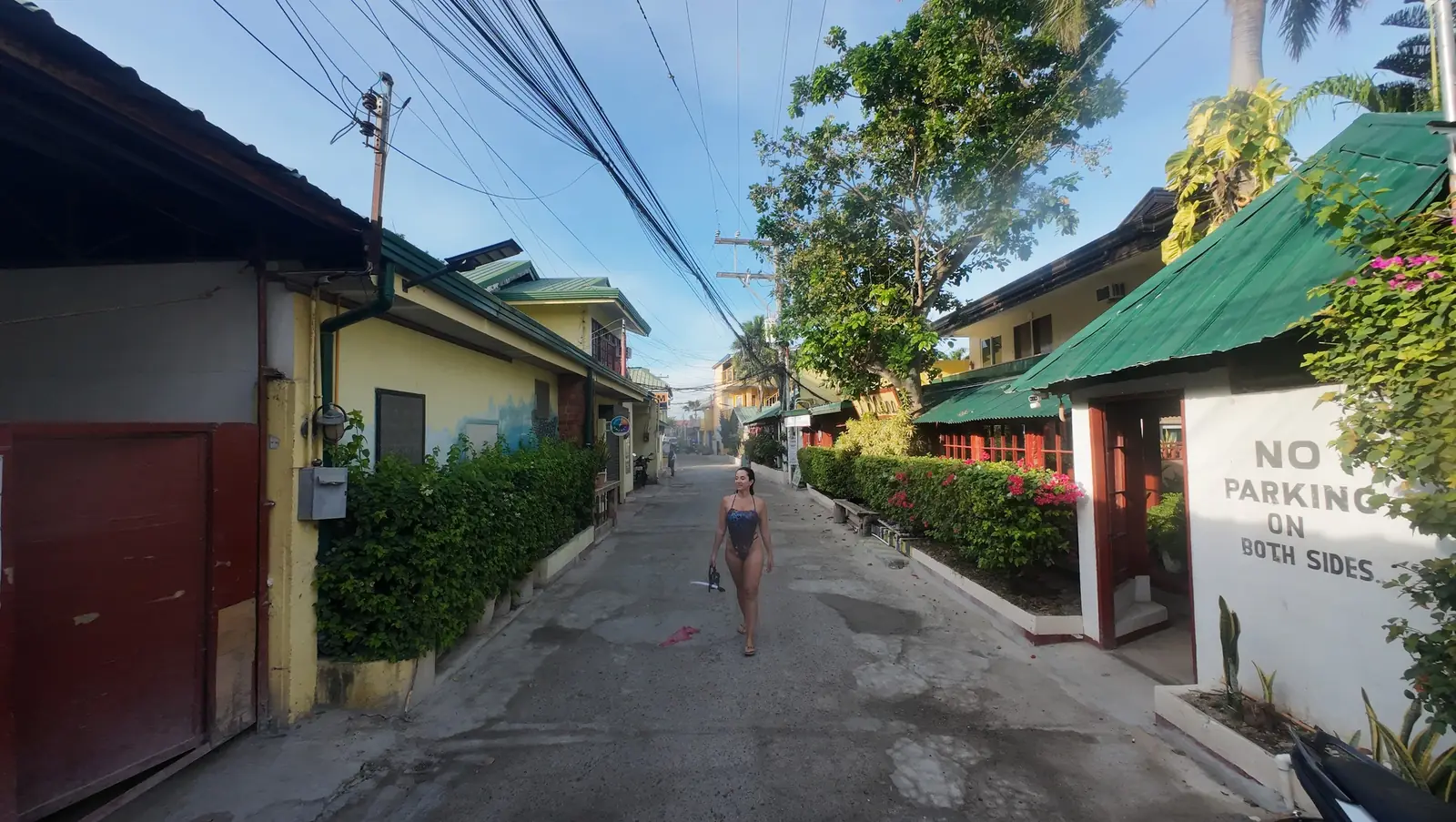 Calle tranquila entre casas bajas y vegetación en Moalboal