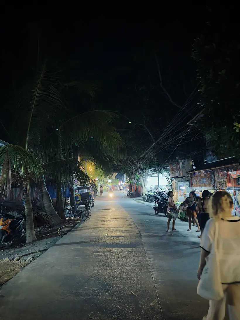 Calle de Moalboal de noche, con palmeras y pocas luces
