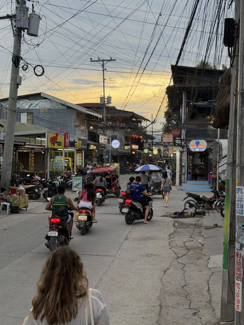 Calle de Moalboal al atardecer con motos, tuk-tuks y pequeños comercios