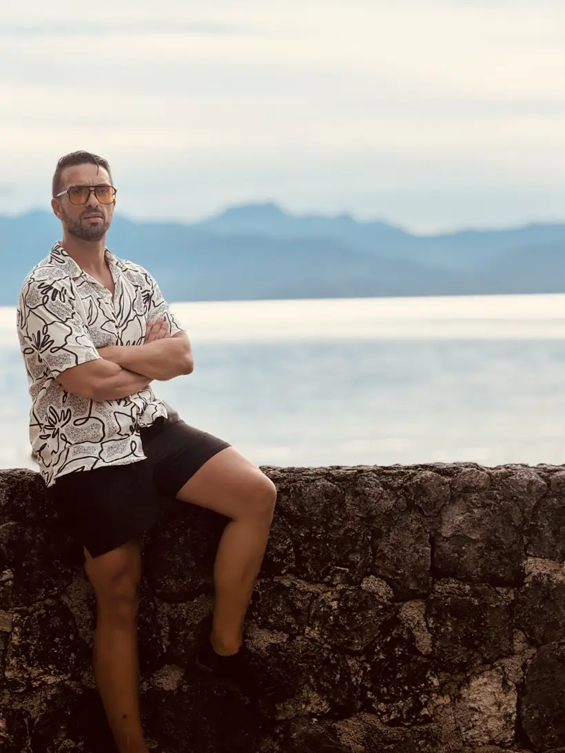 Juan sentado en el muro de piedra frente al mar en Club Serena