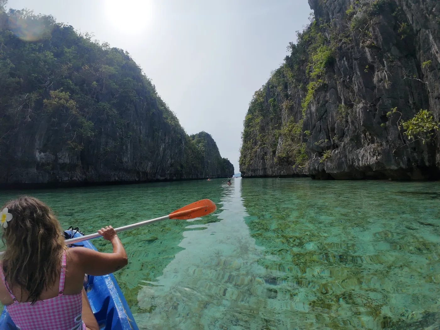 Cristina remando en kayak por agua turquesa entre acantilados de piedra caliza