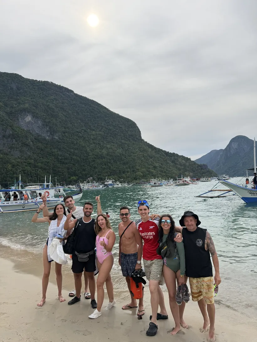 Las ocho personas del grupo del Tour A en la playa, con bangkas y acantilados detrás