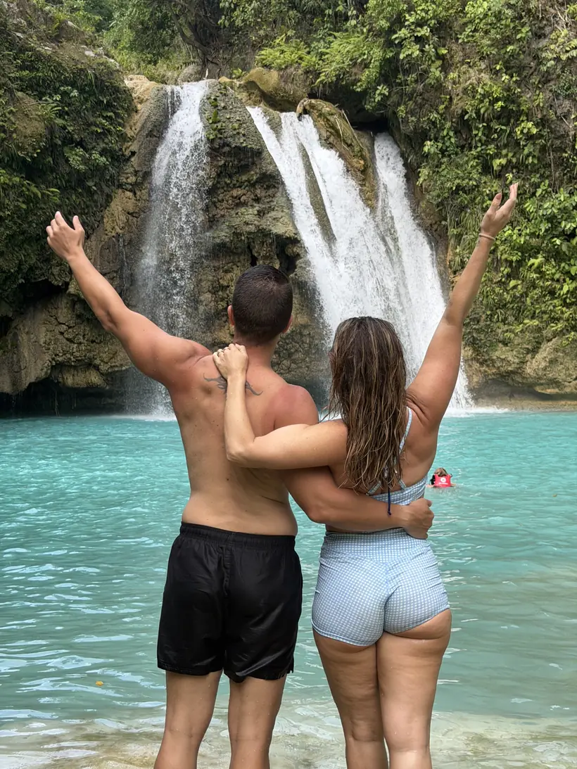 Cristina y Juan de espaldas, abrazados frente a una cascada de Kawasan