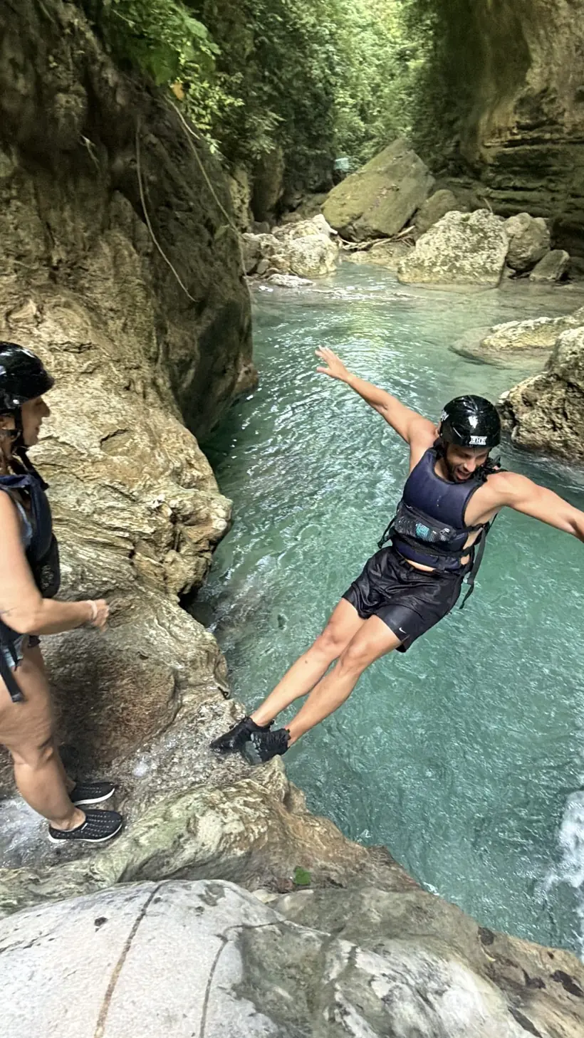 Juan saltando a una poza del cañón mientras Cristina mira desde la roca