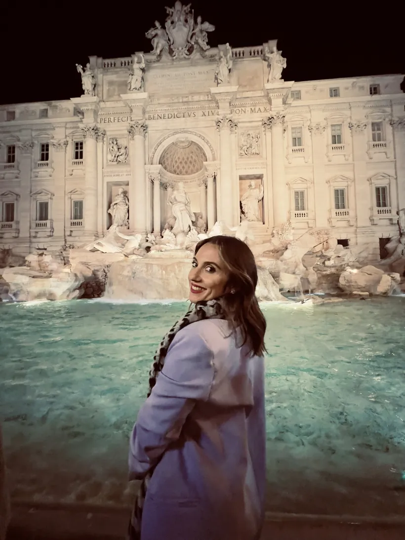 Cristina junto a la Fontana di Trevi iluminada de noche