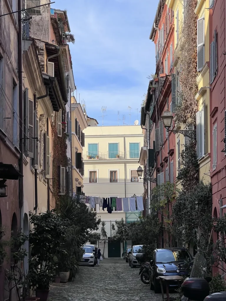 Calle de Trastevere con fachadas de colores y coches aparcados