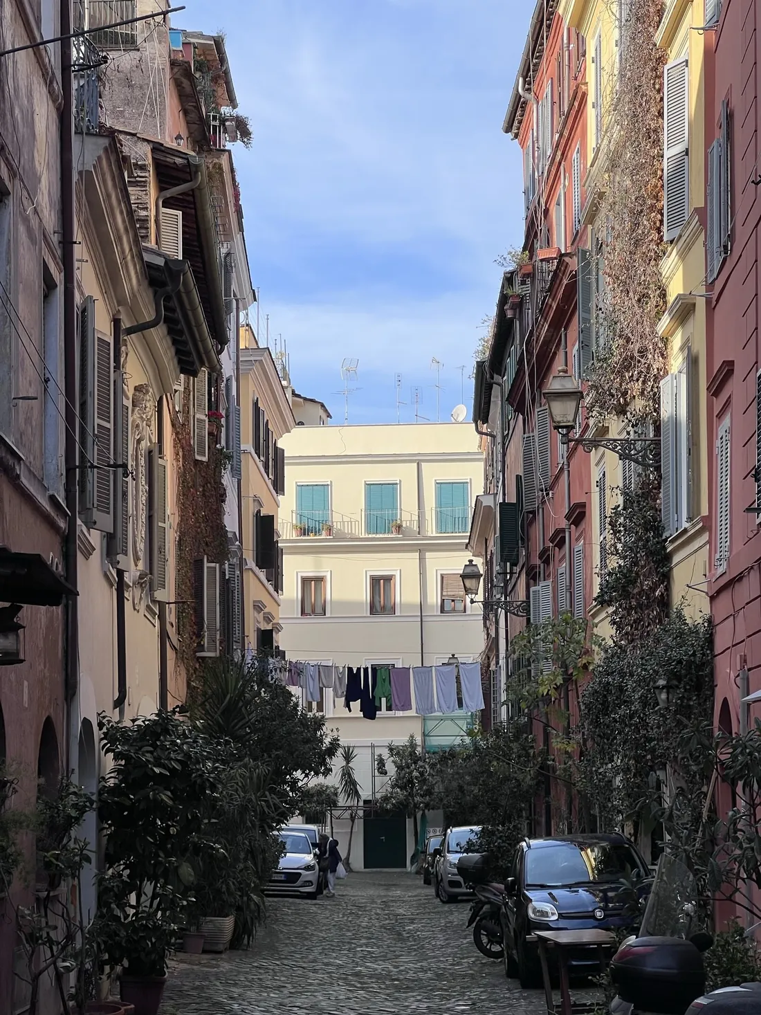 Calle de Trastevere con fachadas de colores y coches aparcados
