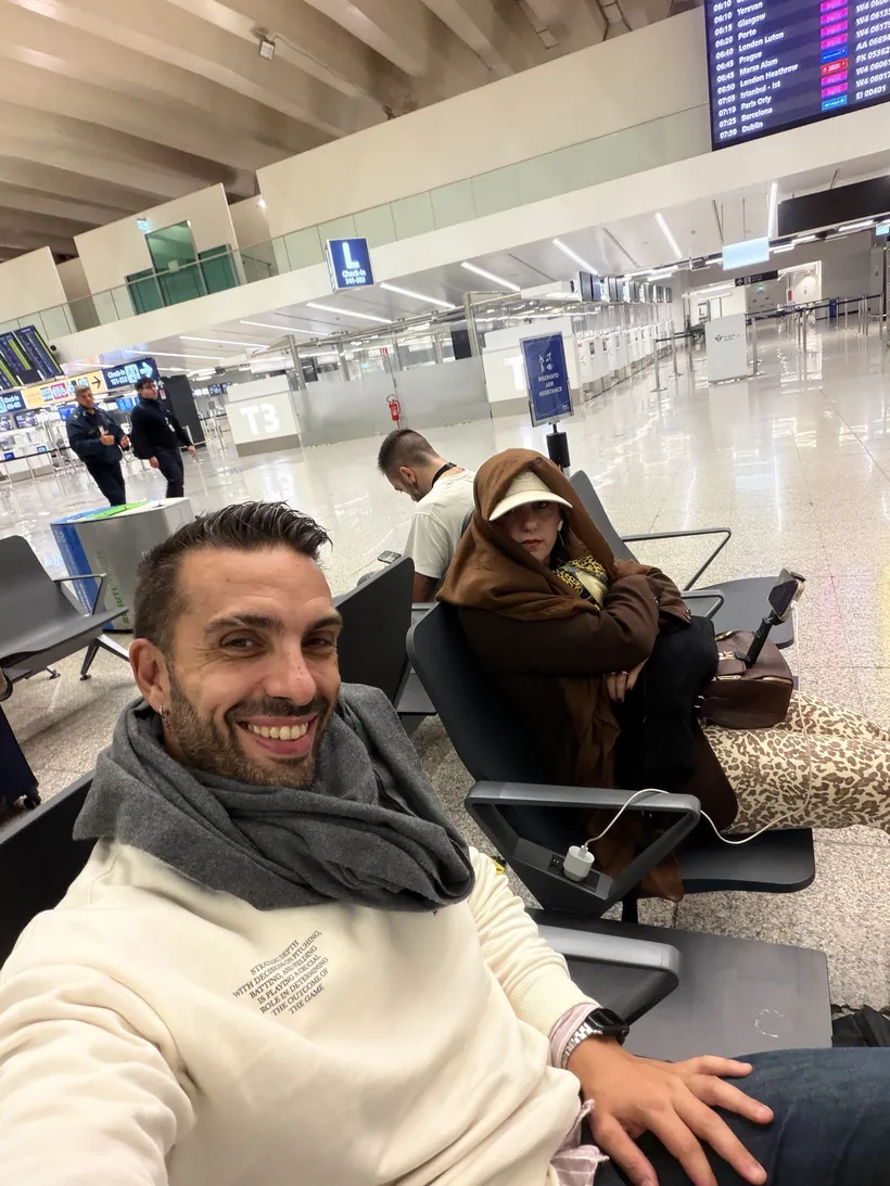 Juan y Cristina sentados en las sillas del aeropuerto de Fiumicino de noche