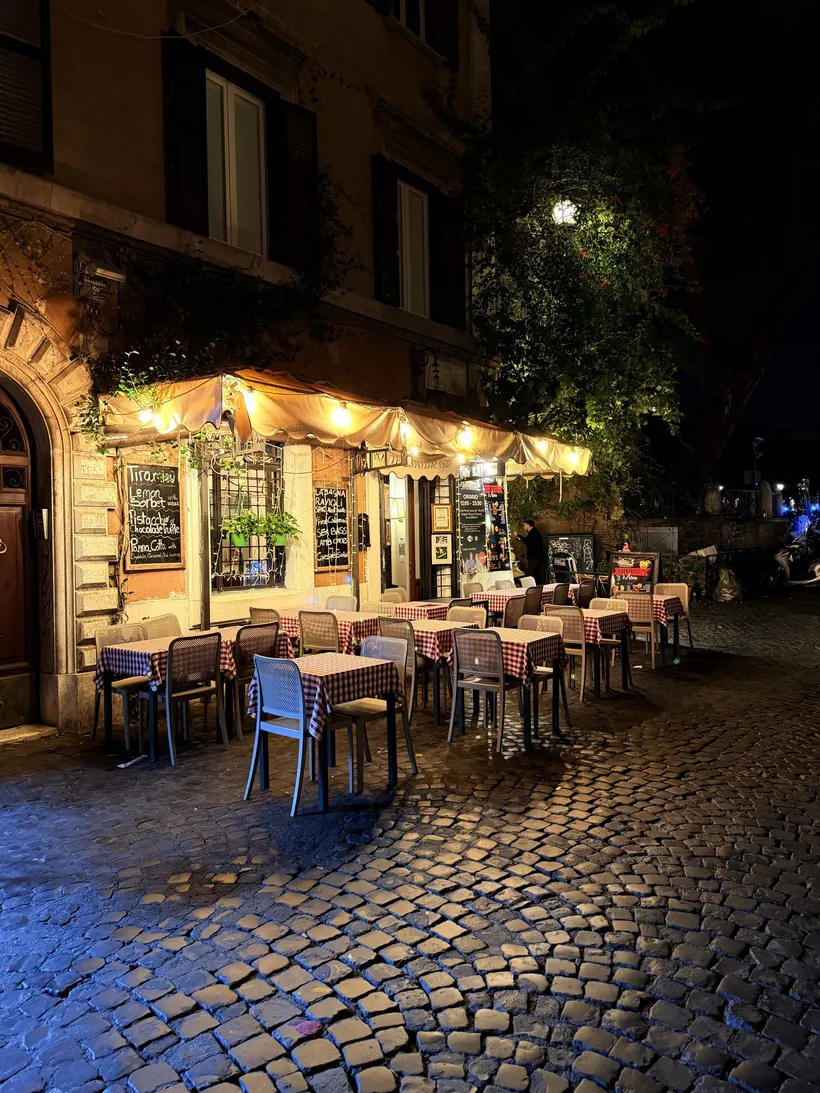 Calle de Trastevere de noche con mesas al aire libre y fachadas iluminadas